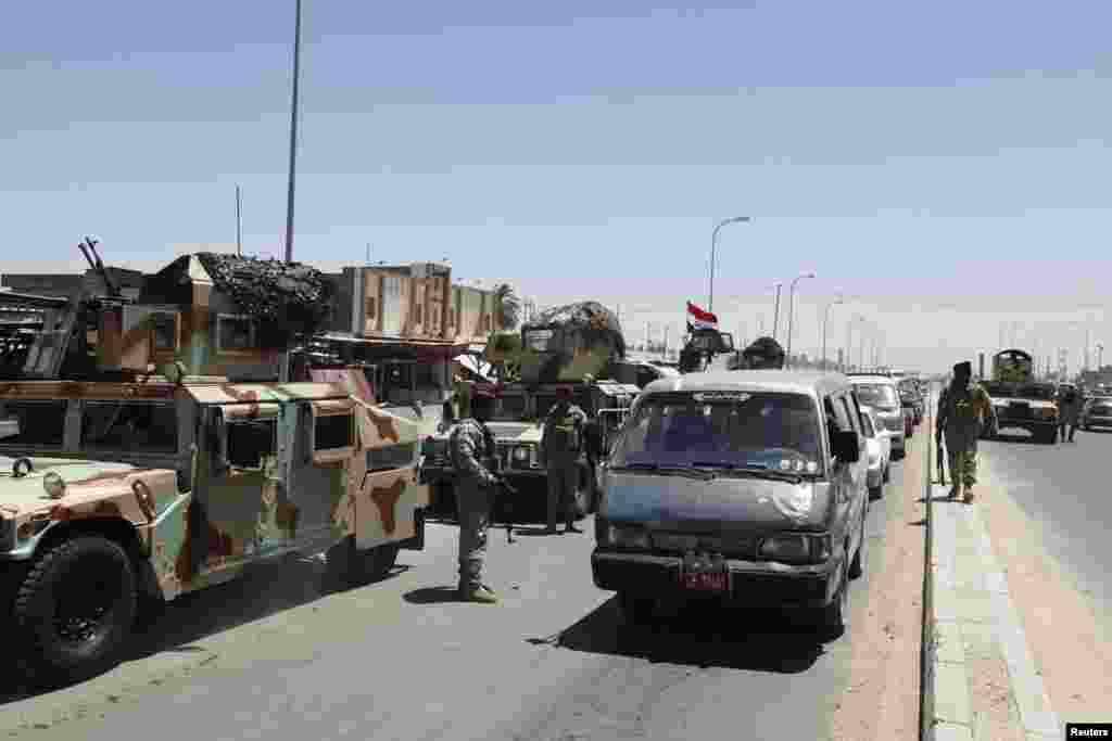 Members of Iraqi security forces take their positions along a road during an intensive security deployment west of Baghdad, June 24, 2014. 