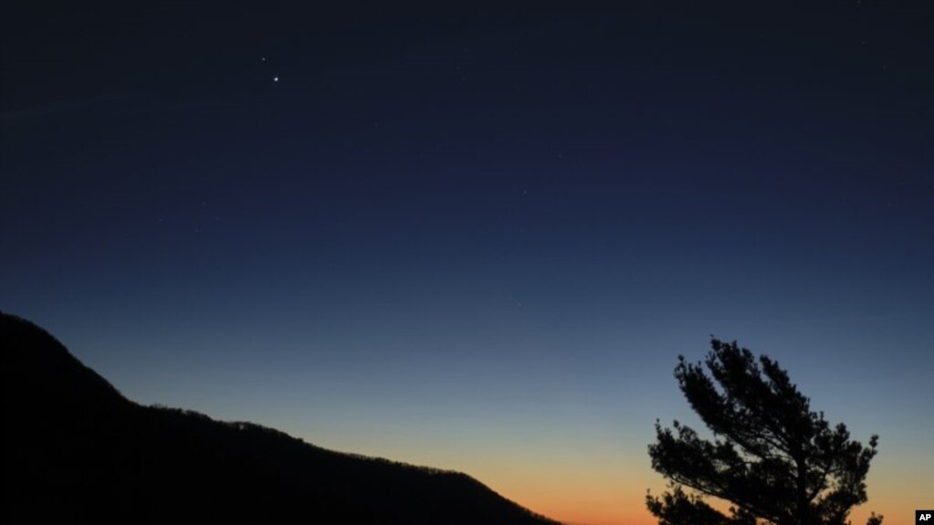 In this Sunday, Dec. 13, 2020 photo made available by NASA, Saturn, top, and Jupiter, below, are seen after sunset from Shenandoah National Park in Luray, Virginia, USA. (Bill Ingalls/NASA via AP)