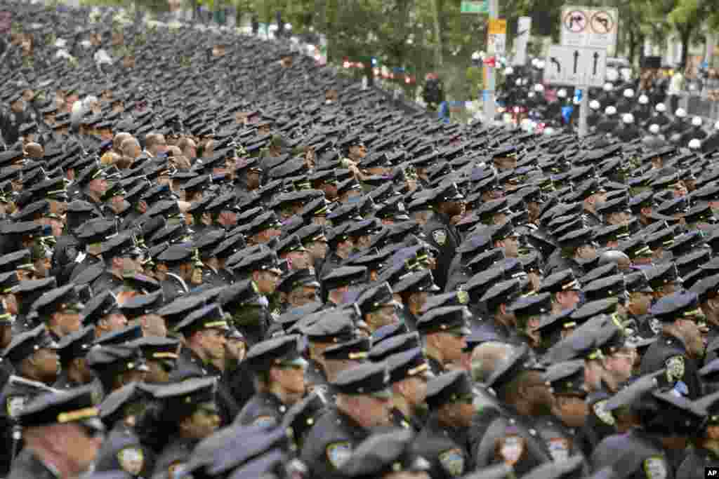 Police officers stand at attention as the funeral procession for slain police officer Miosotis Familia leaves at the World Changers Church after her funeral service in the Bronx borough of New York.