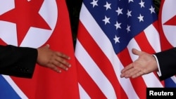FILE - U.S. President Donald Trump and North Korea's leader Kim Jong Un reach to shake hands at the start of their summit at the Capella Hotel on the resort island of Sentosa, Singapore, June 12, 2018.