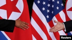 FILE - U.S. President Donald Trump and North Korea's leader Kim Jong Un reach to shake hands at the start of their summit at the Capella Hotel on the resort island of Sentosa, Singapore, June 12, 2018.