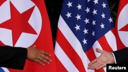 FILE - U.S. President Donald Trump and North Korea's leader Kim Jong Un reach to shake hands at the start of their summit at the Capella Hotel on the resort island of Sentosa, Singapore, June 12, 2018.