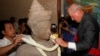 Walter Timoshuk, right, president of Norton Simon Museum of Art in Pasadena, California, places flowers onto a 10th century Cambodian sandstone statue returned from the United States during a handover ceremony at the Council of Ministers in Phnom Penh, Ju