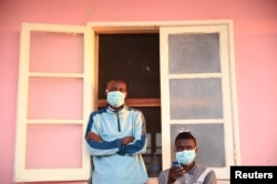 FILE - Tuberculosis patients, wearing masks to stop the spread of the disease, stand outside their ward at Chiulo Hospital, Cunene province, Angola, Feb. 22, 2018.