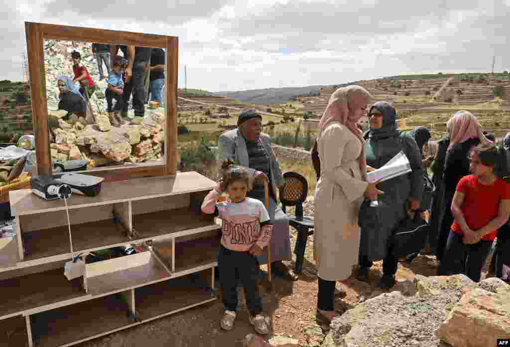 Članovi palestinske porodice proveravaju ostatke svojih stvari nakon što su izraelska postrojenja demolirali kuću koja se nalazi u okupiranoj Zapadnoj obali, gde Izrael zadržava potpunu kontrolu nad planiranjem i izgradnjom. Selo Halhol nalazi se severno od Hebrona. 17. juni, 2021. ( Foto: Hazem Bader / AFP )​