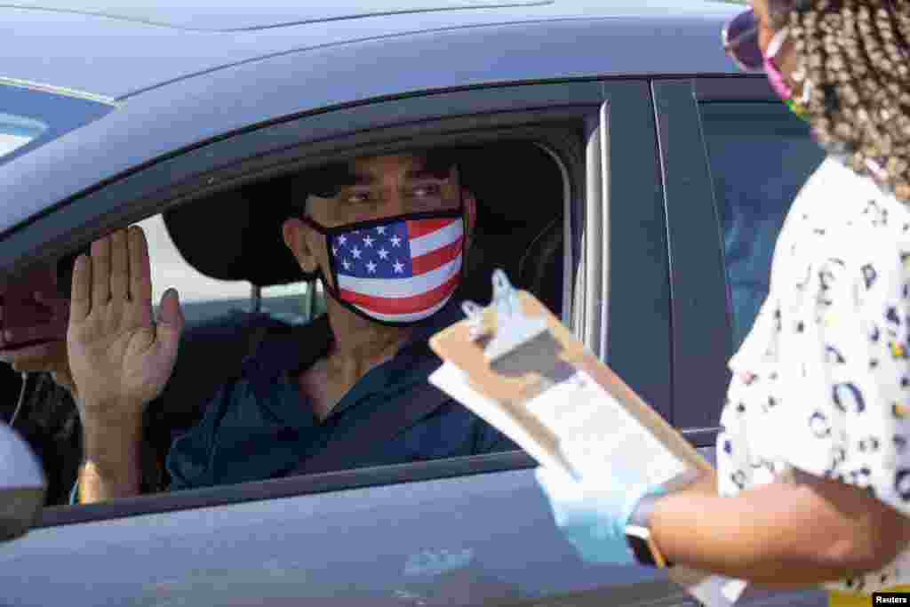 A U.S. immigration officer administers an oath to Palestinian Omar Abdalla during a swearing-in of newly naturalized United States citizens in an empty parking lot in Santa Ana, California, July 29, 2020.