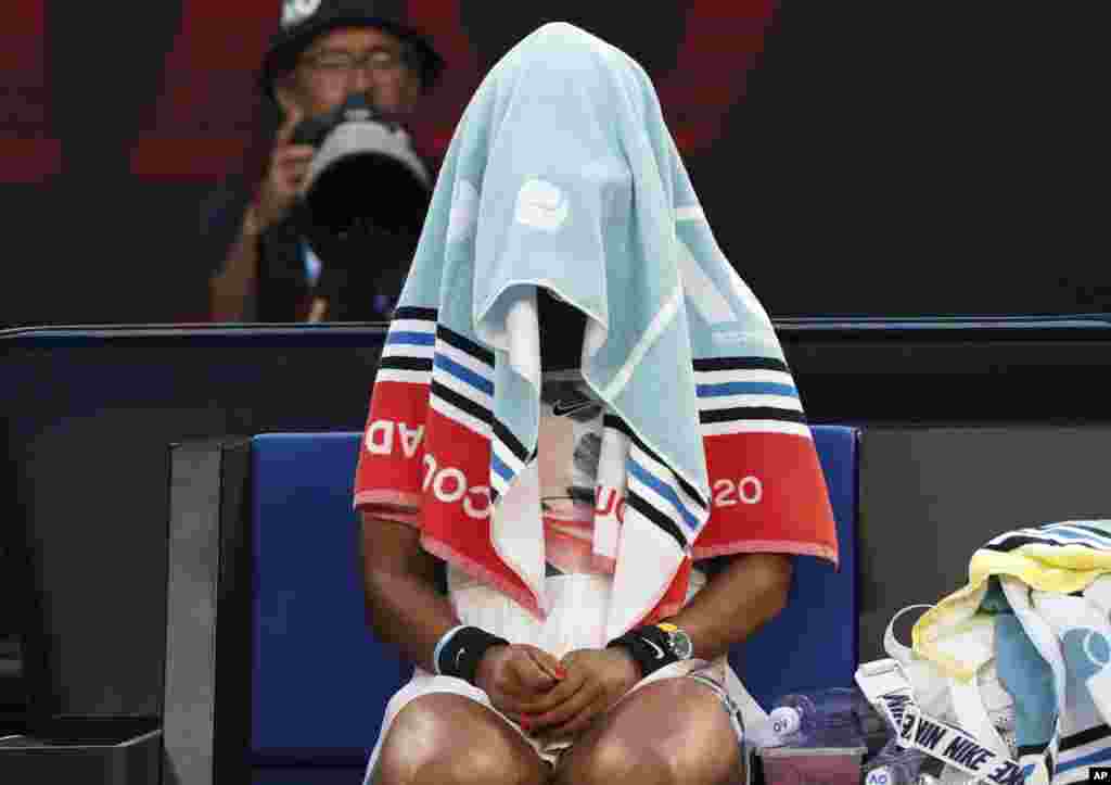 Japan&#39;s Naomi Osaka sits with her towel over her head during a break in her third round loss to Coco Gauff of the U.S. at the Australian Open tennis championship in Melbourne, Australia.