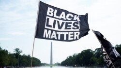 A demonstrator holds a BLM flag during a "Get Your Knee Off Our Necks" march in front of the Lincoln Memorial in support of racial justice that is expected to gather protestors from all over the country in Washington, U.S., August 28, 2020. REUTERS/Erin S