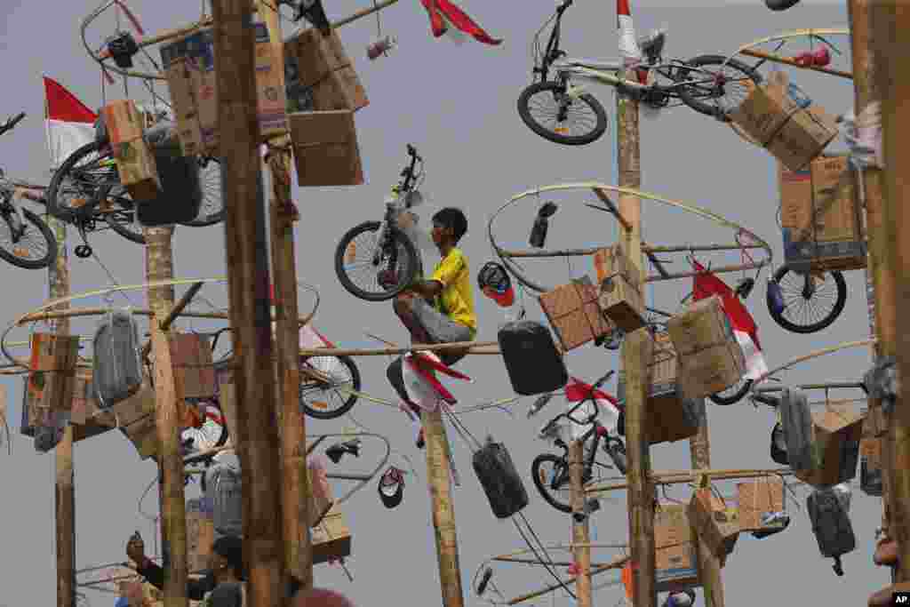 A man retrieves his prize during a greased-pole climbing competition held as part of Independence Day celebrations at Ancol Beach in Jakarta, Indonesia, Aug. 17, 2019.