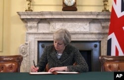 FILE - Britain's Prime Minister Theresa May signs the official letter to European Council President Donald Tusk, in 10 Downing Street, London, March 28, 2017, invoking Article 50 of the bloc's key treaty, the formal start of exit negotiations.