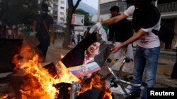 Un manifestante quema un cartel con la imagen de Hugo Chávez durante protestas en Caracas.