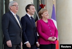 French President Emmanuel Macron, German Chancellor Angela Merkel and European Commission President Jean-Claude Juncker, left, welcome Chinese President Xi Jinping, not pictured, at the Elysee Palace in Paris, March 26, 2019.