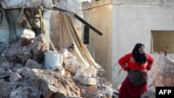一位伊德利卜省的妇女站在被俄罗斯军队空袭炸毁的房屋前。