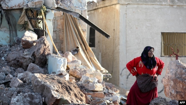 一位伊德利卜省的妇女站在被俄罗斯军队空袭炸毁的房屋前。