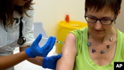 FILE - Dr. Felicity Hartnell, an Oxford University researcher, injects former nurse Ruth Atkins, a volunteer in an experimental Ebola vaccine program, in Oxford, England, Sept. 17, 2014.