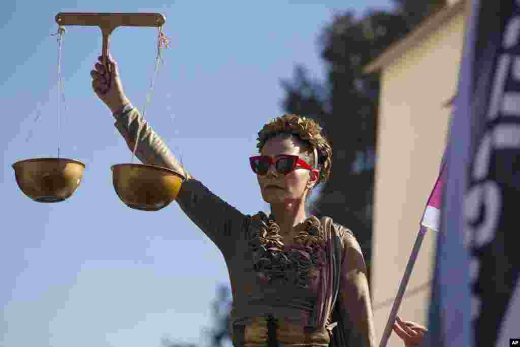 A protester holds the scales of justice outside the District Court during a hearing in Israeli Prime Minister Benjamin Netanyahu&#39;s corruption trial, in Jerusalem.