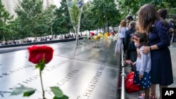 Mourners pause at the north reflecting pool as flowers are placed in the names of the dead at the National September 11 Memorial and Museum, Friday, Sept. 11, 2020, in New York. Americans are commemorating 9/11 as a new national crisis in the form of the