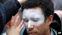 In this Oct. 31, 2018, file photo, a man, who declined to be identified, has his face painted to represent efforts to defeat facial recognition during a protest at Amazon headquarters over the company's facial recognition system, "Rekognition," in Seattle