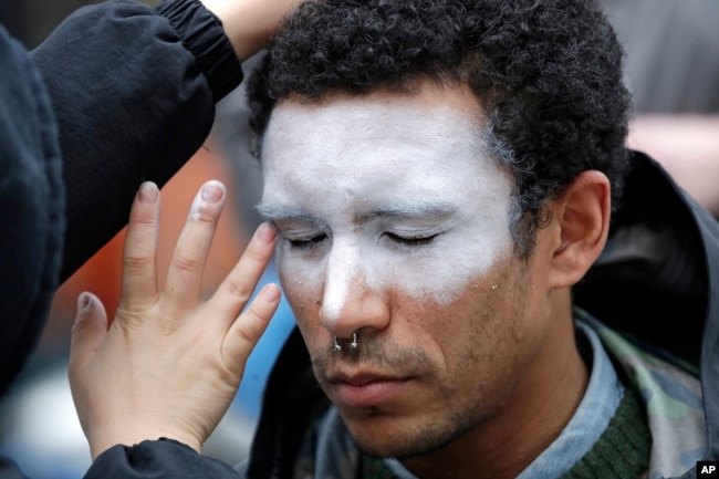 In this Oct. 31, 2018, file photo, a man, who declined to be identified, has his face painted to represent efforts to defeat facial recognition during a protest at Amazon headquarters over the company's facial recognition system, "Rekognition," in Seattle. (AP Photo/Elaine Thompson, File)