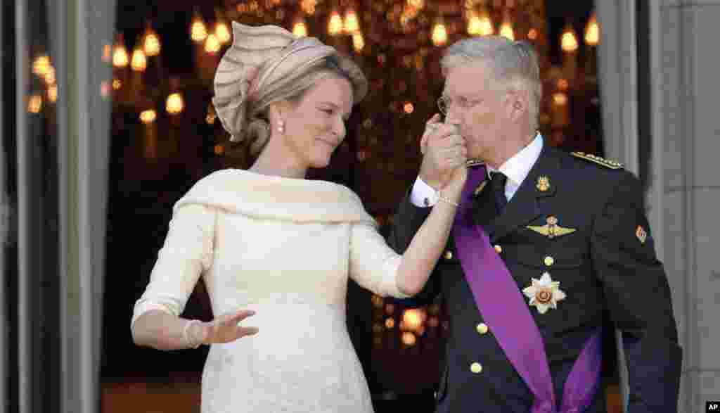 Belgium&#39;s King Philippe, right, kisses the hand of Queen Mathilde as they stand on the balcony of the royal palace in Brussels. Philippe has taken the oath before parliament to become the country&#39;s seventh king after his father Albert abdicated.