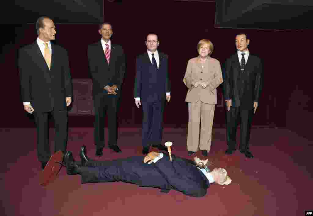 The wax statue representing Russian President Valadimir Putin, whose head was damaged by an activist of the Femen feminist group, lies on the floor next to wax statues of Spain's King Juan Carlos (L), U.S. President Barack Obama (2ndL), French President Francois Hollande (C), German Cancellor Angela Merkel (2ndR) and Morocco's King Mohamed VI (R) at the Grevin museum in Paris, France.