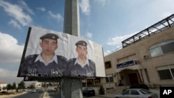 Two posters with pictures of Jordanian pilot, Lt. Muath al-Kaseasbeh, who is held by Islamic State group militants, and Arabic that reads "we are all Muath," hang on a street pole, in front of the captured pilot's tribal gathering place, in Amman, Jordan,