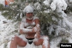 Nikolai Bocharov, 77, a member of the Cryophile winter swimmers club, rubs snow on his body as he sits on a snowdrift after bathing in the icy water of the Yenisei River in the Siberian city of Krasnoyarsk, Russia, Nov. 21, 2015.