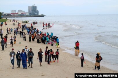 Warga berkumpul di pantai untuk membersihkan pantai dari tumpahan minyak di Pantai Kilang Mandiri di Balikpapan, Kalimantan Timur, 4 April 2018. (Foto: Antara/Sheravim via REUTERS)
