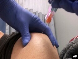 A patient receives a vaccine, Dec. 8, 2016, at a Boston area medical clinic.