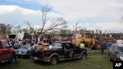 Dozens of people gather to help with cleanup efforts at a farm that was severely damaged by a tornado Sunday, May 10, 2015, in Delmont, South Dakota.