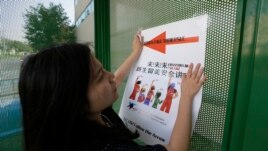 FILE - Ailu Xu, a graduate student from China, posts a sign directing Chinese students to new student orientation at the University of Texas at Dallas in Richardson, Texas, Aug. 22, 2015.