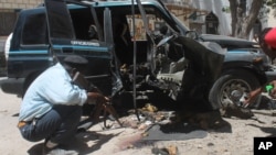 A Somali police officer looks at the wreckage of the car in Mogadishu, Somalia, Monday, April, 21, 2014.