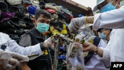 Para petugas memeriksa salah satu dari 49 kontainer yang berisi sampah, limbah plastik, dan bahan-bahan beracun yang melanggar aturan impor di Batam, 19 Juni 2019. (Foto: AFP)
