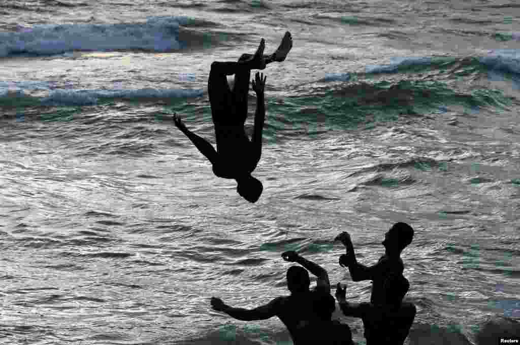 A man is flipped into water by others at a beach in Colombo, Sri Lanka.