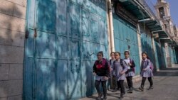 Palestinian children walk past closed souvenir shops, at the tourists market adjacent to the Church of the Nativity, in the West Bank city of Bethlehem, Tuesday, Nov. 16, 2021. (AP Photo/Nasser Nasser)