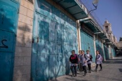 Anak-anak Palestina berjalan melewati toko-toko suvenir yang tutup, di pasar turis yang berdekatan dengan Gereja Kelahiran Yesus (the Church of Nativity), di kota Betlehem, Tepi Barat, Selasa, 16 November 2021. (AP Photo/Nasser Nasser)