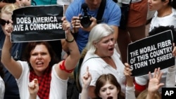 Women hold signs as they protest the separation of immigrant families, June 28, 2018, inside the Hart Senate Office Building on Capitol Hill in Washington.