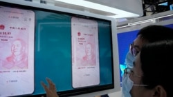 Visitors look at the e-CNY, a digital version of the Chinese Yuan, displayed during a trade fair in Beijing, China, Sunday, Sept. 5, 2021. (AP Photo/Ng Han Guan)