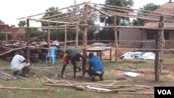 Workers use locally available material to put up a new structure at the orphanage. (S.P. Apiku/VOA)