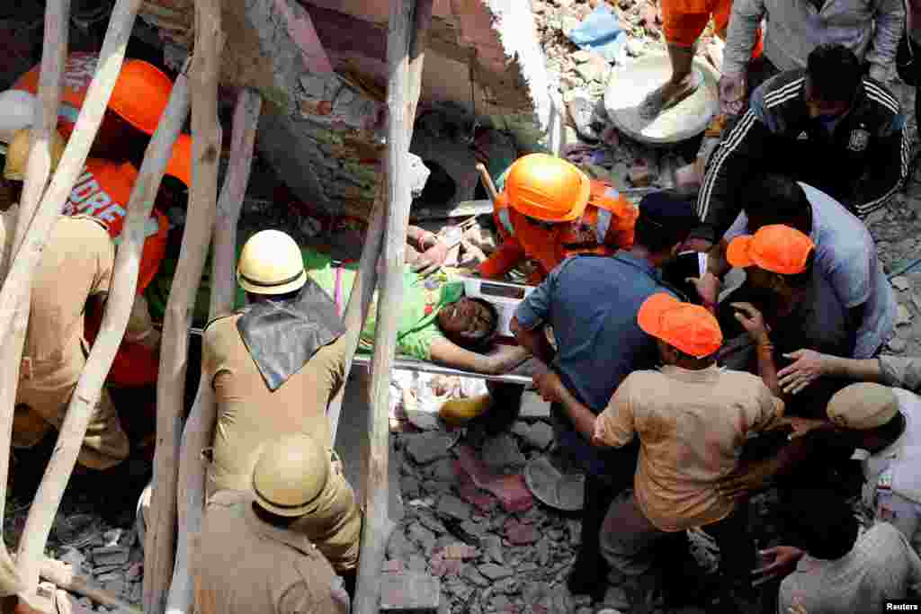Rescuers carry a survivor amidst the rubble after a building collapsed in New Delhi, India.