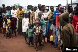 FILE - South Sudanese people wait at a transit centre in Koluba before boarding courtesy buses to Imvepi refugee settlement camp in Arua District, northern Uganda, Aug. 12, 2017.