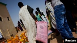 FILE - A man walks away with a bag of rice at a food distribution center run by the Spanish NGO Accion Contra el Hambre (Action Against Hunger) in Tarenguel, Mauritania, May 30, 2012.