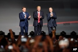 FILE - President Donald Trump stands with National Rifle Association Executive Vice President Wayne LaPierre, right, and Chris W. Cox, executive director of the National Rifle Association Institute for Legislative Action as he arrives for the National Rif