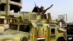 FILE - This image taken from video shows an Islamic State militant waving upon his arrival in Beiji, north of Baghdad, June 17, 2014.