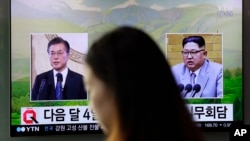 FILE - A visitor walks by a TV screen showing file footage of South Korean President Moon Jae-in, left, and North Korean leader Kim Jong Un, right, during a news program at the Seoul Railway Station in Seoul, South Korea, March 29, 2018. 