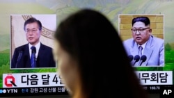A visitor walks by a TV screen showing file footage of South Korean President Moon Jae-in, left, and North Korean leader Kim Jong Un, right, during a news program at the Seoul Railway Station in Seoul, South Korea, March 29, 2018. 