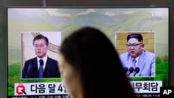 FILE - A visitor walks by a TV showing file footage of South Korean President Moon Jae-in, left, and North Korean leader Kim Jong Un during a news program at the Seoul Railway Station in Seoul, South Korea, March 29, 2018.