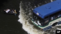 Residents travel on a boat as a bus drives on a flooded street in Bangkok, Thailand, November 5, 2011.