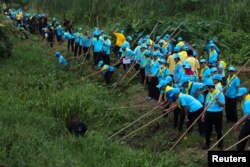 King's volunteers wearing blue caps and yellow foulards clean a canal in Bangkok, Aug. 8, 2018.