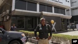 Pakistani police officer stands guard at the office of Axact software company in Karachi, May 27, 2015.